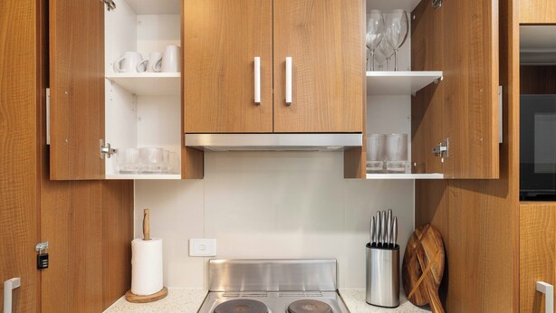 Una cocina con armarios de madera, estufa de acero inoxidable y un bloque de cuchillos.