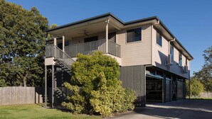 A two-story house with a covered balcony, a garage, and a fenced yard. - Modern Rocklea 1BR | AC | Kitchen | 121D1 (Rocklea)