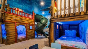A children's play area with a ship-themed play structure, a slide, and a bunk bed. - Legends Coastal Sanctuary: Private Pool, Theater, Near Disney (Kissimmee)