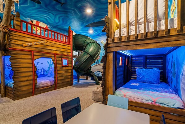 A children's play area with a ship-themed play structure, a slide, and a bunk bed. - Legends Coastal Sanctuary: Private Pool, Theater, Near Disney (Kissimmee)