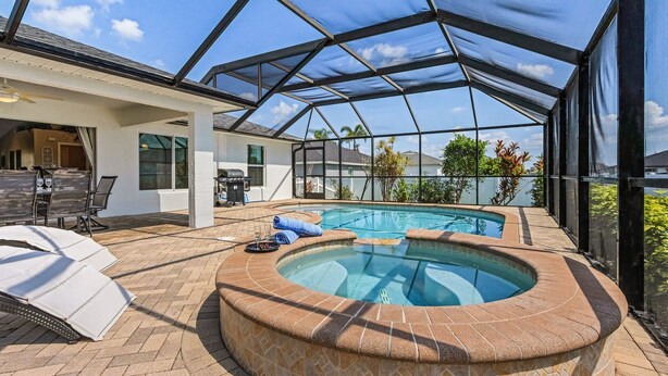 An outdoor swimming pool area with a hot tub, covered patio, and seating. - Relax & Unwind in Privacy - Heated Salt Water Pool and Spa - Villa Belle Vie (Cape Coral)