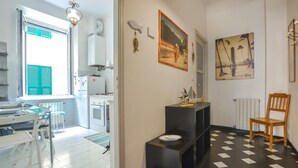 Una cocina moderna con electrodomésticos blancos, una zona de comedor con mesa y sillas, y obras de arte en las paredes.