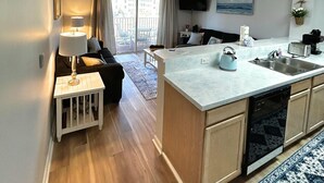 Una cocina moderna con una isla central, un rincón de comedor con sofá y vistas al exterior a través de grandes ventanales.