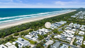 Vista aerea di una zona residenziale costiera con case moderne, una spiaggia e cielo sereno.