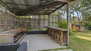 Relax in a covered patio with a bench and wooden seating.
