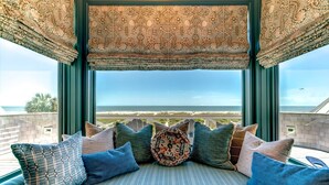 Ein Balkon mit Blick auf das Meer, einer gemusterten Markise und verschiedenen Kissen.