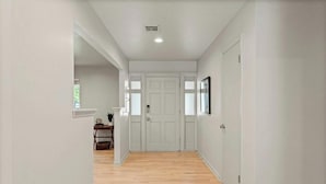 A hallway with white walls, a wooden floor, and a double door at the end. - La Casa @ La Fortune/St. Francis (Tulsa)