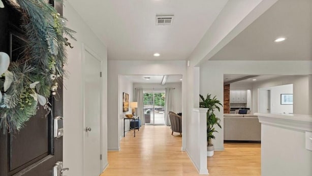 A modern interior with a wooden floor, white walls, and a kitchen area visible in the background. - La Casa @ La Fortune/St. Francis (Tulsa)