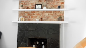 A modern living room with a fireplace, white shelves, and a brick wall. - Trail Side Cottage (Clare)