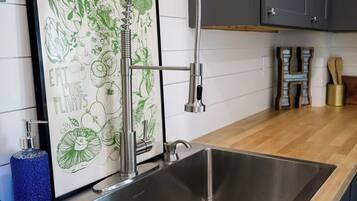 A kitchen with a stainless steel sink, a framed botanical illustration, and wooden cabinets.