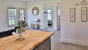 A modern kitchen with a wooden countertop, a round mirror, and a view to the dining area. - Hunts Bend: Feel the Season Change|5-Acre Retreat (Bowling Green)