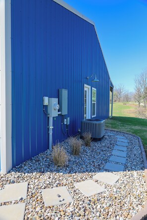 Een gebouw met een blauwe gevel, een buitenunit voor airconditioning en een pad van stenen dat naar de ingang leidt.
