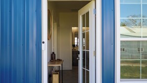 A doorway leading into a building with a blue exterior wall, a small table with items on it, and a window with a view of the outside. - Hunts Bend: Feel the Season Change|5-Acre Retreat (Bowling Green)
