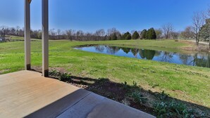 A covered outdoor area with a pond, grassy field, and trees in the background. - Hunts Bend: Feel the Season Change|5-Acre Retreat (Bowling Green)