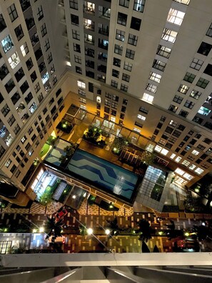 A high-rise building with multiple floors, balconies, and a central courtyard with a swimming pool.