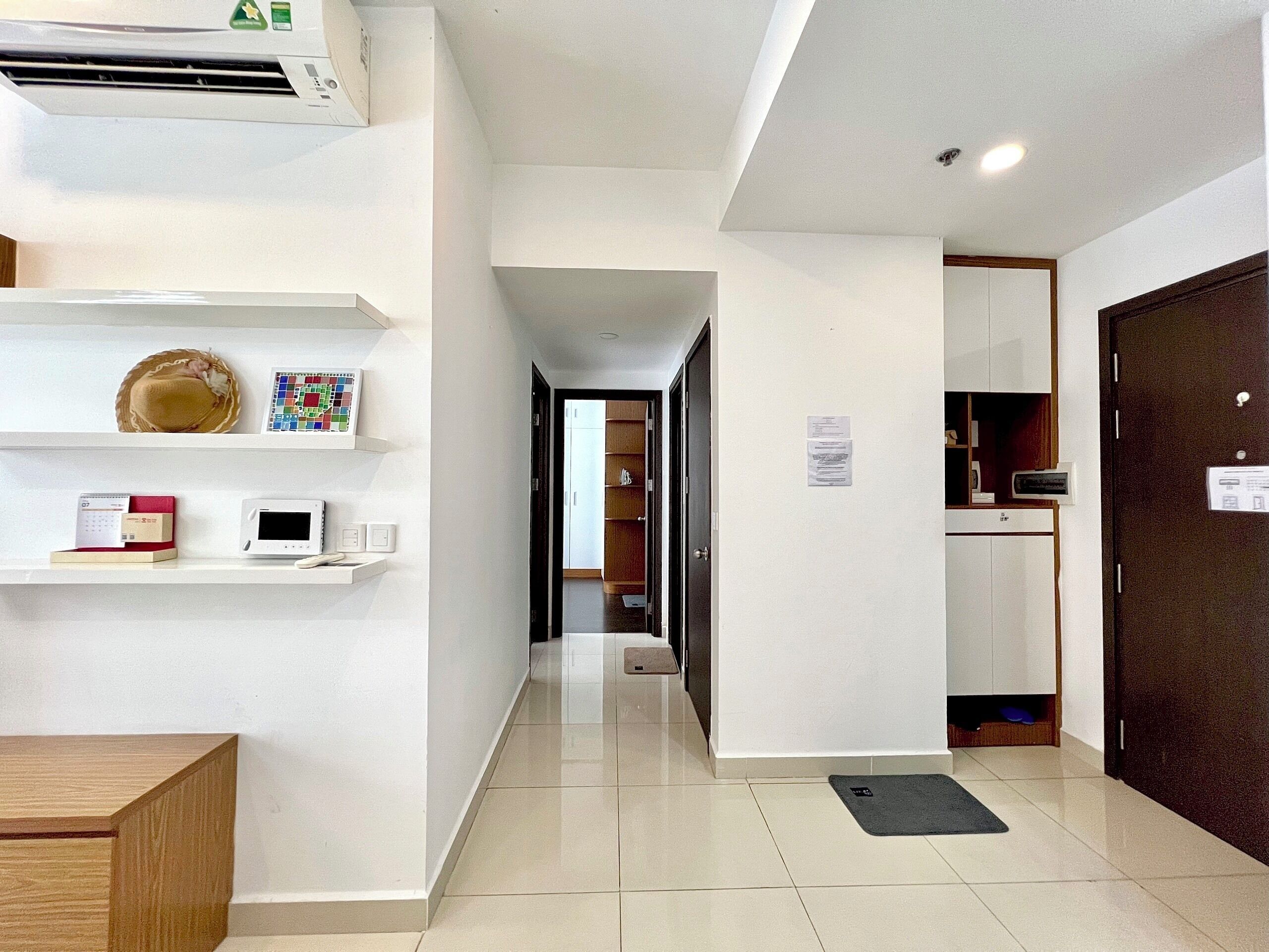 Un couloir d’hôtel avec un comptoir de réception, un porte-manteau, un tableau d’affichage et une porte donnant accès à une chambre.