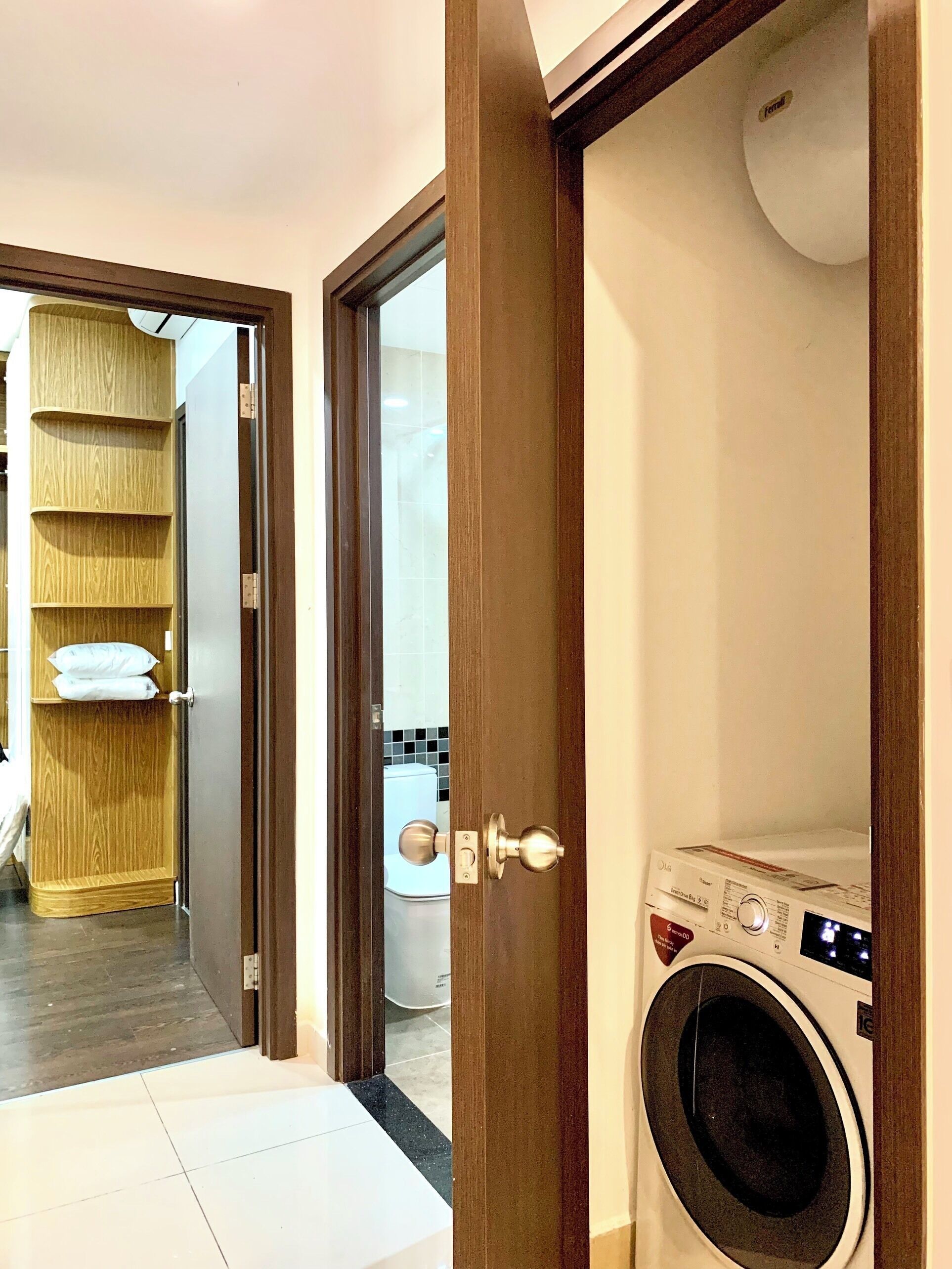 Een wasserette met een wasmachine, een houten garderobe met planken en een betegelde vloer.