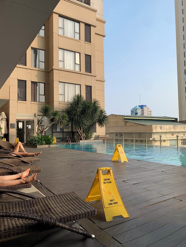 A poolside area with lounge chairs and a wet floor sign.