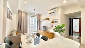 A modern living room with a dining area, featuring a large table, chairs, and a potted plant. - Golden Apartment (Ho Chi Minh City)
