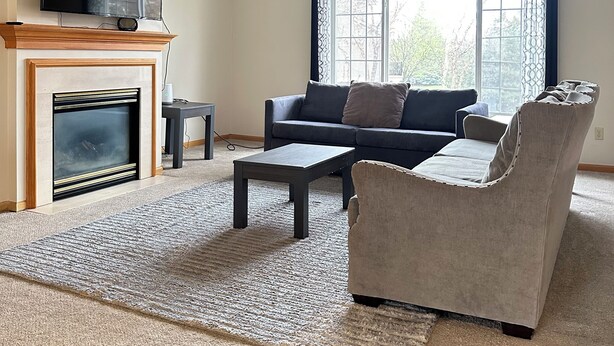 Ein Wohnzimmer mit Kamin, einer Couch, einem Couchtisch und einem Fernseher, der über dem Kamin angebracht ist.
