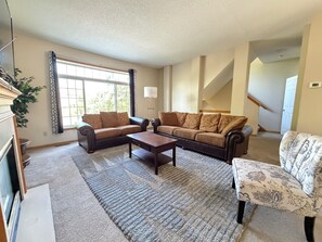 Ein Wohnzimmer mit zwei Sofas, einem Couchtisch und einem gemusterten Sessel.
