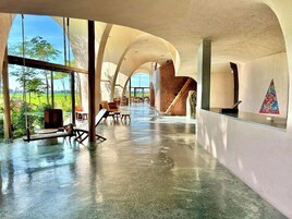 Un interior amplio y moderno, con techo curvo y ventanas grandes que ofrecen vistas a un paisaje verde.