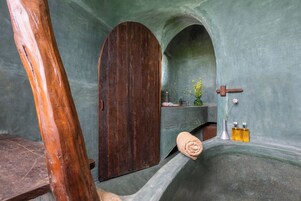 Un baño con puerta de madera, un lavamanos, una toalla y dos botellas de líquido.