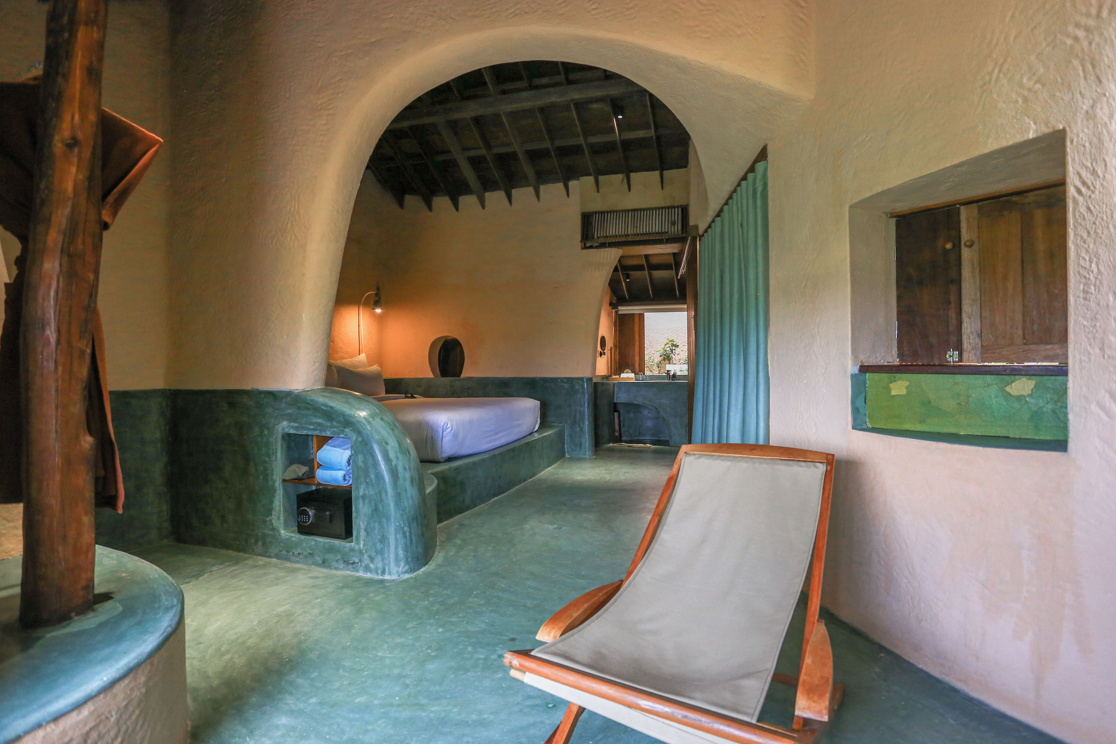 Une pièce rustique avec un plafond voûté, un lit, une chaise et une petite table.