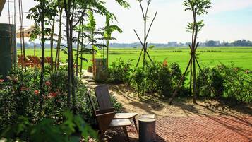 A garden patio with a wooden chair, a small table, and a trash bin.