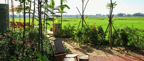 A garden patio with a wooden chair, a small table, and a trash bin.