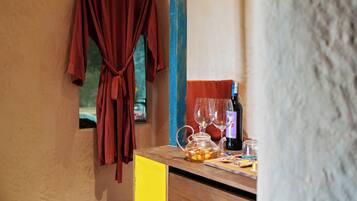 A room with a wooden counter, a red robe hanging on the wall, and a bottle of wine on the counter.