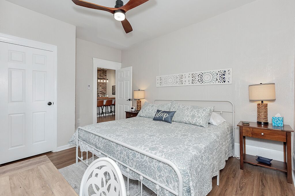 A bedroom with a bed, a nightstand, a lamp, and a ceiling fan.