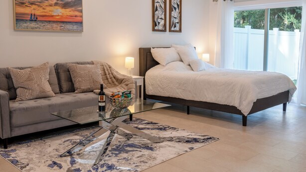 Une chambre moderne avec un lit, un canapé, une table basse en verre et un tableau au mur.
