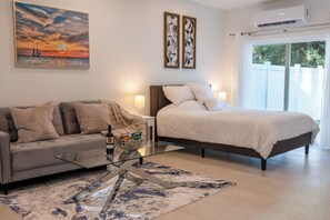 Une chambre moderne avec un lit, un canapé, une table basse en verre et un tableau au mur.