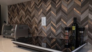 Une cuisine au design moderne, dotée d’un crédence ornée d’un motif en chevrons, d’une machine à café intégrée et d’un porte-épices avec des bocaux.