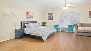 A bedroom with a bed, a desk, a chair, a sofa, and a ceiling fan. - Stylish Modern House  4BR/3BA  Home in McKinney (McKinney)