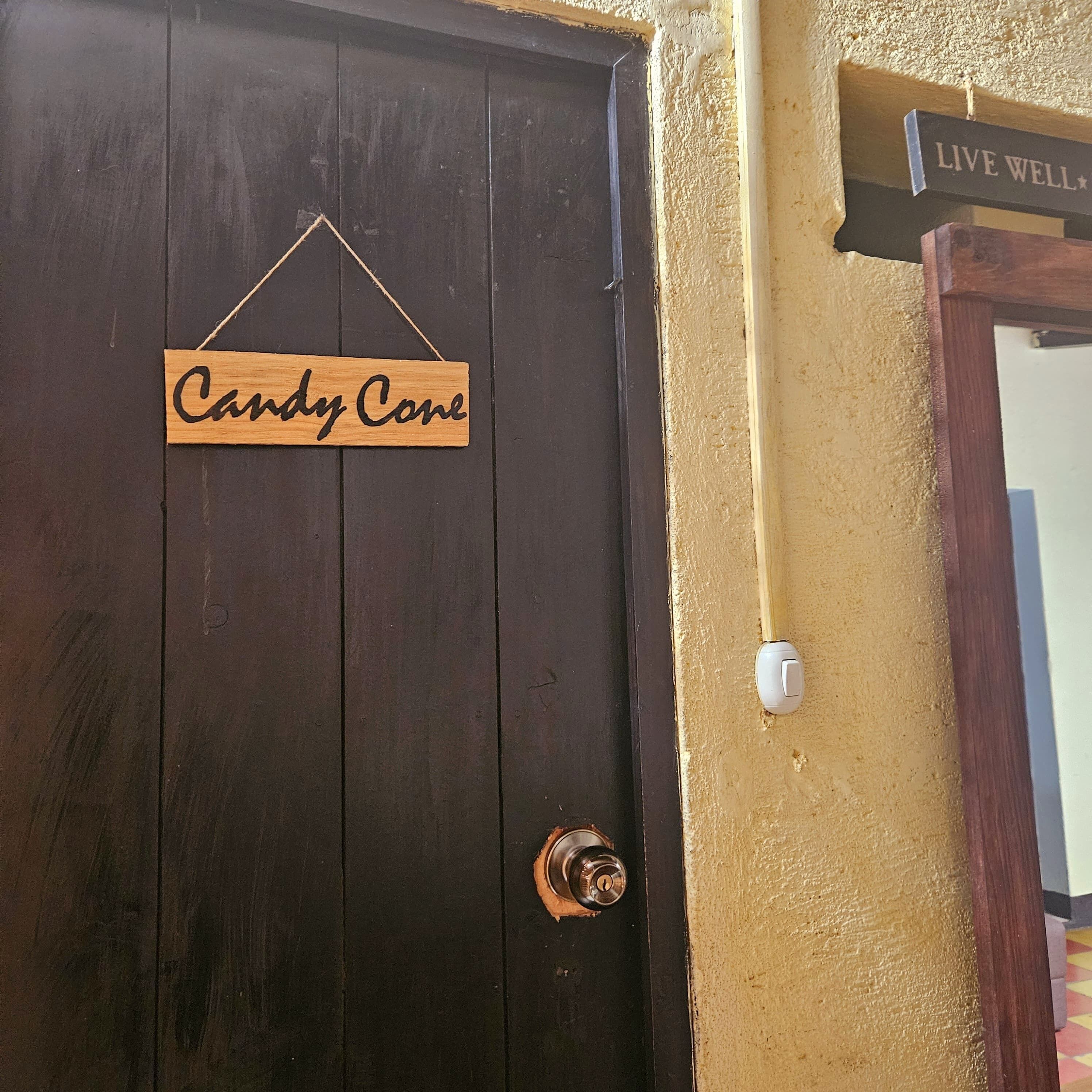 A dark wooden door with a sign reading "Candy Cane" hanging on it.