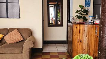 Un hall de hotel con un cartel de recepción, un mostrador de madera, un sofá y una mesa de registro.