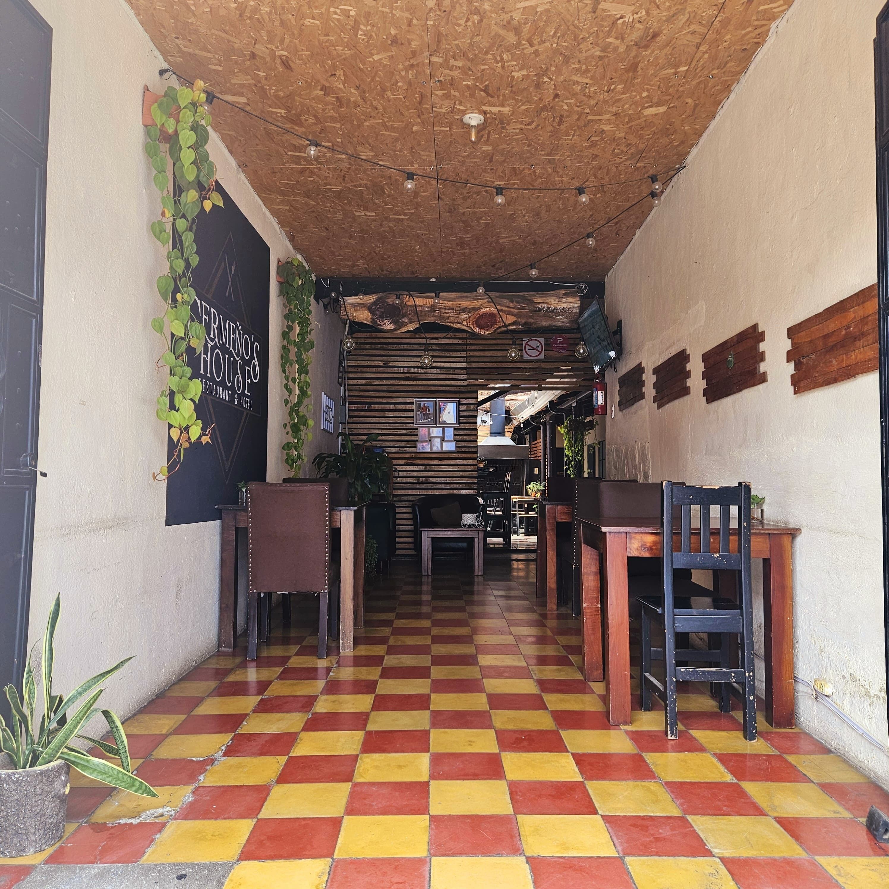 Un restaurante con suelo a cuadros, techo de madera y plantas colgantes.