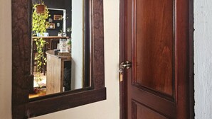 Une porte en bois sur laquelle est affiché un panneau indiquant « Candy Cove », et un miroir qui reflète une pièce où l’on aperçoit une plante suspendue et une table en bois.