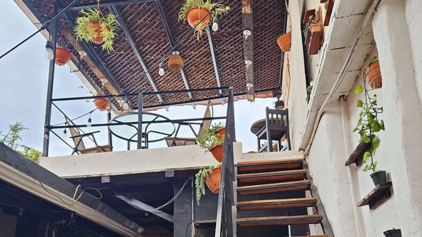 Un intérieur rustique avec un escalier en bois, des plantes en pot et un sol carrelé.
