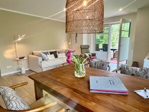 Een moderne woonkamer met een houten eettafel, een bank en een hanglamp.