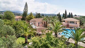 A residential property with a swimming pool, lush greenery, and a view of distant hills.