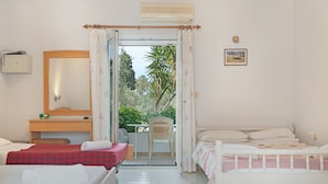 A bedroom with two beds, a chair, a small table, a mirror, and a view of the outdoors.