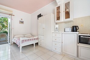A compact room with a bed, a kitchenette, and a sliding glass door leading to a balcony. - Apartment 'Sea View 4' with Shared Pool, Wi-Fi and Air Conditioning (Kefalonia)