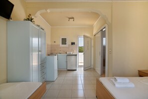 Habitación de hotel con cama, kitchenette pequeña, baño y vista al exterior.