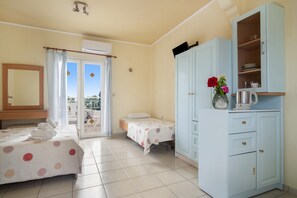 Un dormitorio con dos camas, un armario, un baño con espejo y un balcón con vistas.