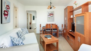 A modern living room with a sofa, dining table, and wooden cabinets. - Apartment 'M - 1' with Shared Pool, Private Terrace and Wi-Fi (Torrox costa)