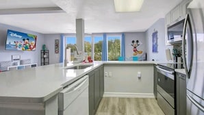A modern kitchen with a large island, stainless steel appliances, and Disney-themed decor.