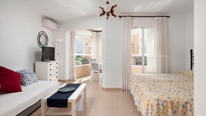 A bedroom with a bed, a desk, a chair, a TV, and a balcony view. - Studio Apartment 'Estudio Bloque 89' with Sea View, Wi-Fi and Air Conditioning (Torrox)
